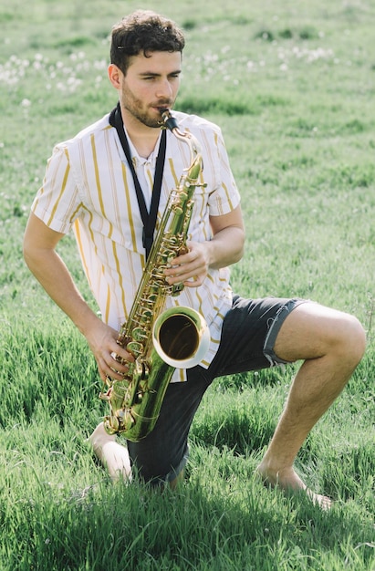 Photo un jeune homme beau joue du saxophone à l'extérieur