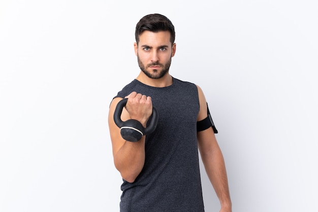 Jeune homme beau sport avec barbe sur blanc faisant de l'haltérophilie avec kettlebell