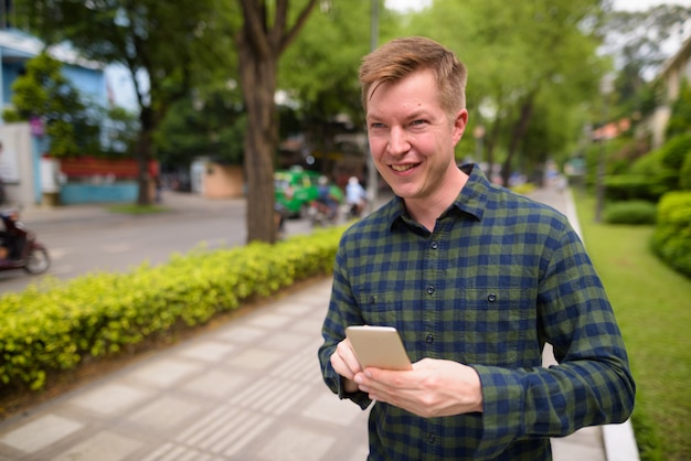 Jeune homme beau touriste à l'aide de téléphone mobile au Vietnam