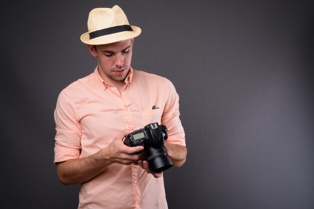 Jeune homme beau touriste contre le mur gris