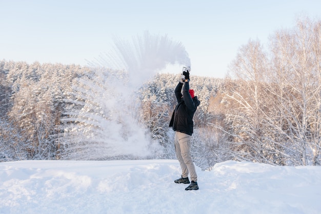 Un jeune homme bénéficie d'une journée d'hiver sur le fond d'une forêt couverte de neige