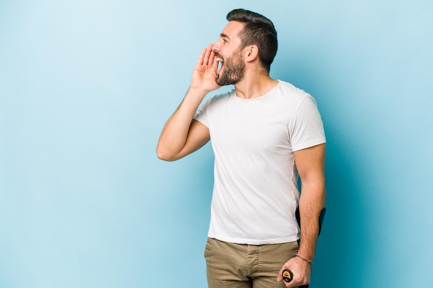 Jeune homme avec des béquilles isolé sur fond bleu criant et tenant la paume près de la bouche ouverte