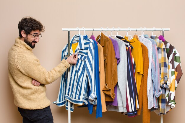 Jeune homme berded cool avec des vêtements contre le mur plat