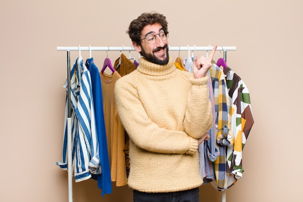 Jeune homme berded cool avec des vêtements sur le mur