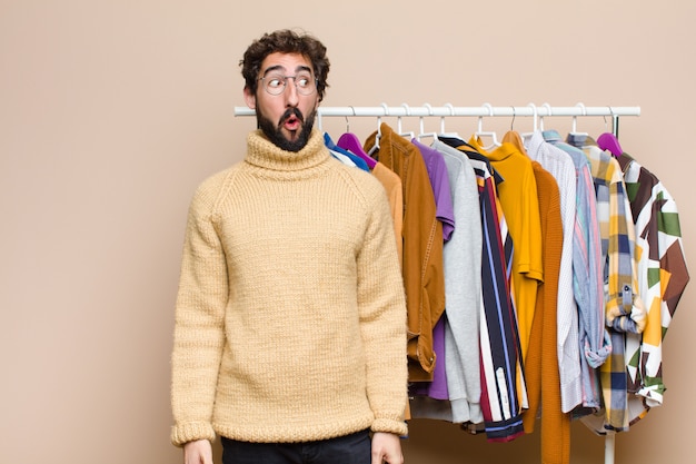 Jeune homme berded cool avec des vêtements sur le mur