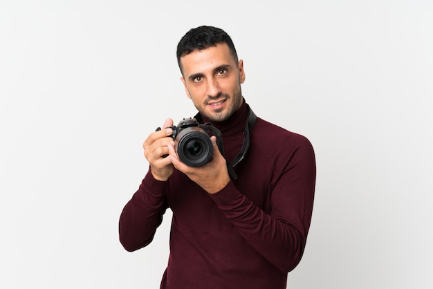 Jeune homme blanc isolé avec une caméra professionnelle