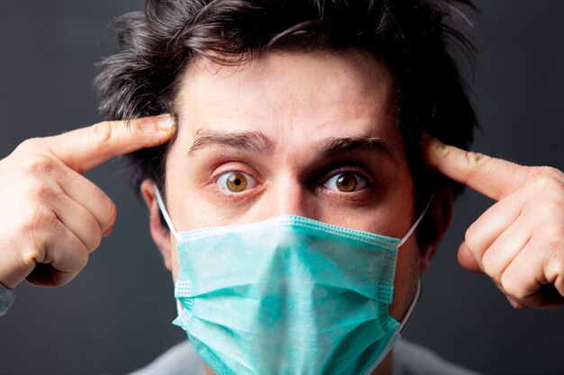 Jeune homme blanc en masque de protection sur fond sombre