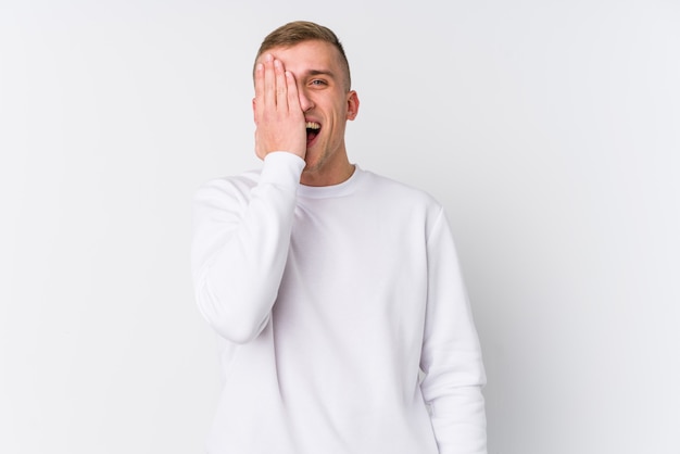 Jeune homme sur blanc s'amuser couvrant la moitié du visage avec la paume.