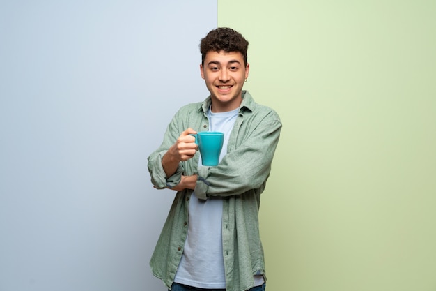 Jeune homme sur bleu et vert tenant une tasse de café