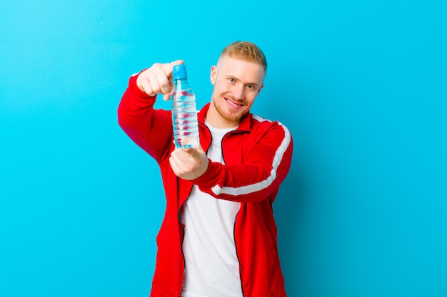 Jeune homme blond avec une bouteille d'eau portant des vêtements de sport