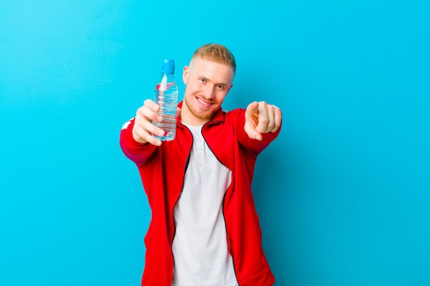 Jeune homme blond avec une bouteille d'eau portant des vêtements de sport