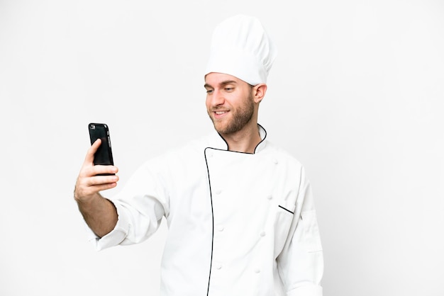 Jeune homme blond Chef sur fond blanc isolé faisant un selfie