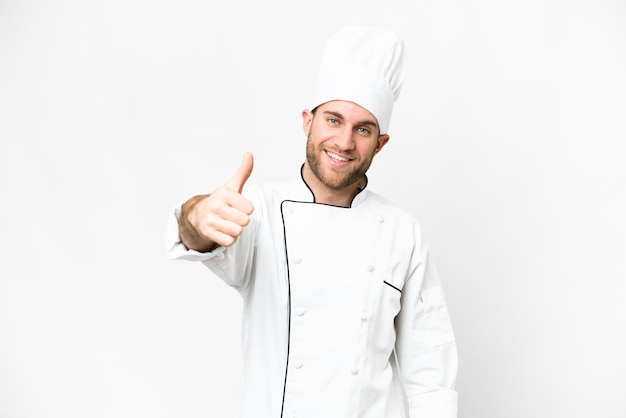 Jeune homme blond Chef sur fond blanc isolé avec les pouces vers le haut parce que quelque chose de bien s'est produit