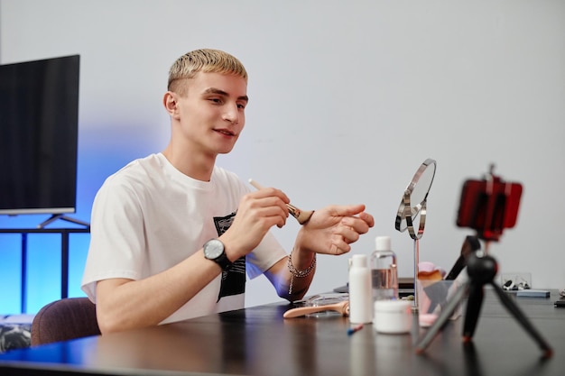 Jeune homme blond filmant un tutoriel de beauté