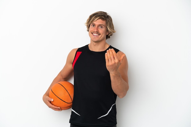 Jeune homme blond isolé sur un mur blanc jouant au basket et faisant le geste à venir