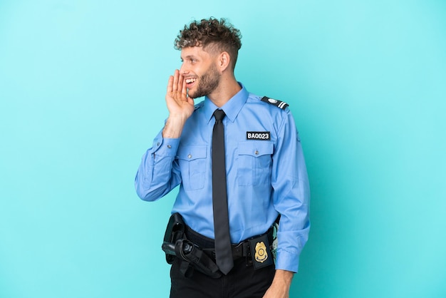 Jeune homme blond policier isolé blanc sur fond bleu criant avec la bouche grande ouverte sur le côté