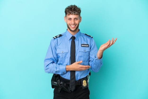 Jeune homme blond policier isolé blanc sur fond bleu tendant les mains sur le côté pour inviter à venir