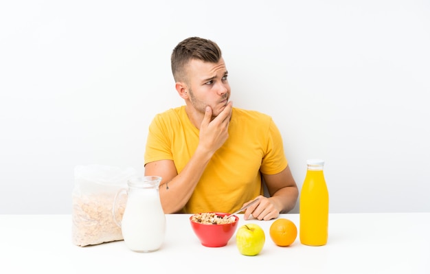 Jeune homme blond prenant son petit déjeuner en pensant à une idée