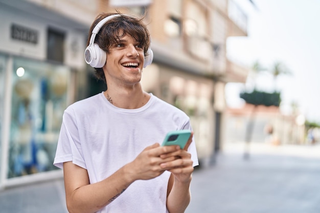 Jeune homme blond souriant confiant écoutant de la musique dans la rue