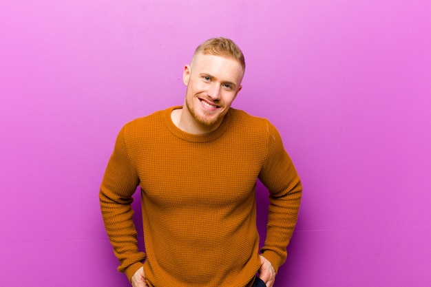 jeune homme blond souriant avec une expression confiante et détendue