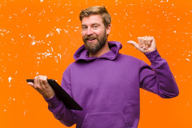 Jeune homme blond avec une tablette portant un sweat à capuche violet