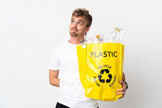 Jeune homme blond tenant un sac de recyclage plein de papier à recycler isolé