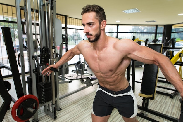 Jeune homme Bodybuilder travaille sur sa poitrine avec câble croisé dans une salle de sport