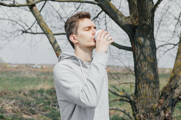 Jeune homme boit du café dans la nature