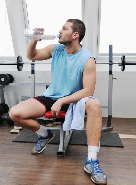 jeune homme boit de l'eau à l'entraînement de remise en forme au club de sport