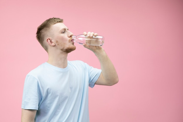 Jeune homme boit de l'eau provenant d'une bouteille