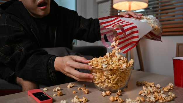 Jeune homme avec un bol de pop-corn regardant un film la nuit Concept d'activités de divertissement et de loisirs