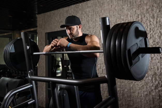 Jeune homme en bonne santé au repos dans la salle de sport du club sain après l'exercice