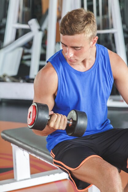 jeune homme en bonne santé exerçant avec haltère au gymnase