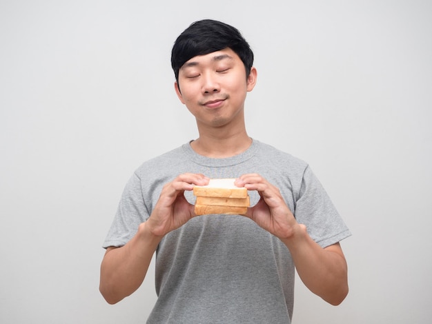 Un jeune homme en bonne santé ferme les yeux tenant un sandwich dans le portrait de la main