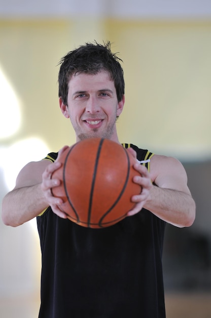 un jeune homme en bonne santé joue au basket-ball dans la salle de sport de l'école