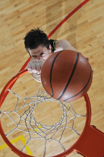 un jeune homme en bonne santé joue au basket-ball dans la salle de sport de l'école