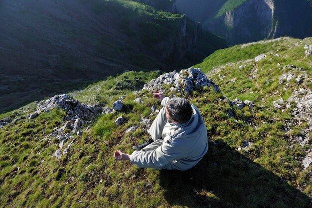 un jeune homme en bonne santé pratique le youga en montagne en hauteur tôt le matin et au lever du soleil