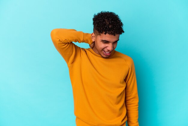 Jeune homme bouclé afro-américain sur bleu souffrant de douleurs au cou en raison d'un mode de vie sédentaire.