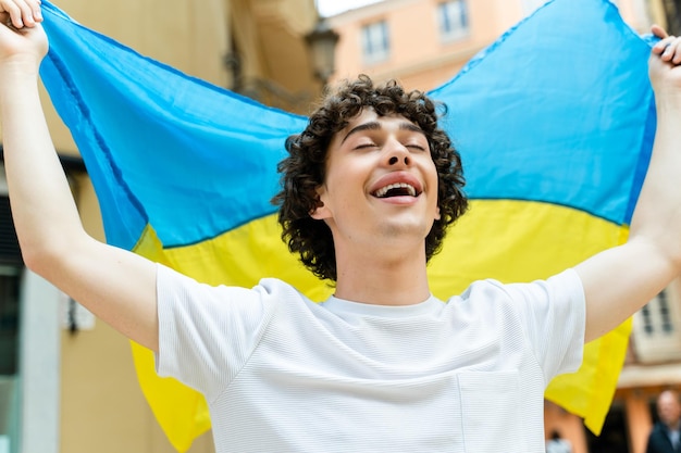 Jeune homme bouclé drapé aux couleurs du drapeau ukrainien dans la rue