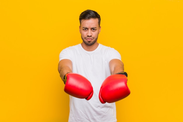 Jeune homme boxeur sud-asiatique avec des gants rouges.