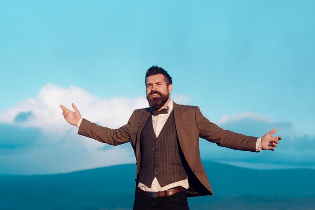 Jeune homme branché et cool debout à l'extérieur de la cigarette portant une chemise contre le ciel bleu