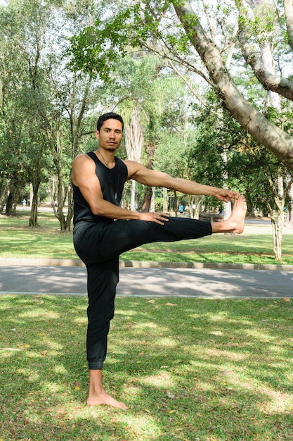 Jeune homme brésilien face à la caméra, dans une position équilibrée, dans un parc public par une journée ensoleillée.