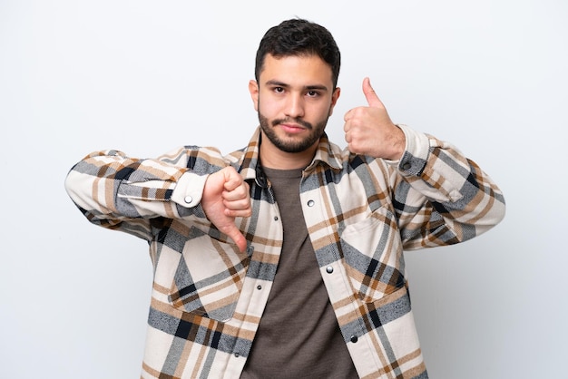 Jeune homme brésilien isolé sur fond blanc faisant bon signe indécis entre oui ou non