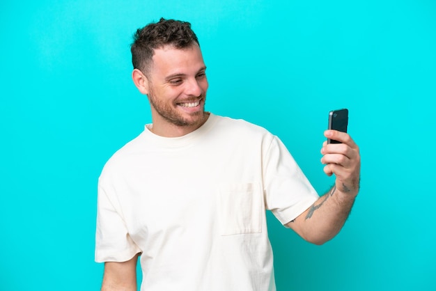 Jeune homme brésilien isolé sur fond bleu faisant un selfie