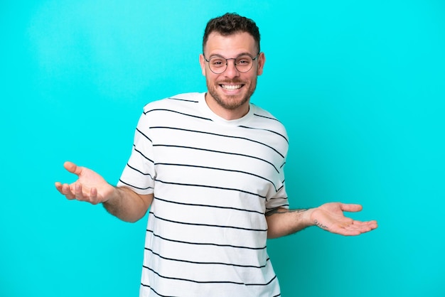 Jeune homme brésilien isolé sur fond bleu heureux et souriant