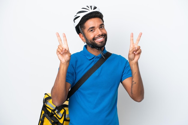 Jeune homme brésilien avec sac à dos thermique isolé sur fond blanc montrant le signe de la victoire avec les deux mains