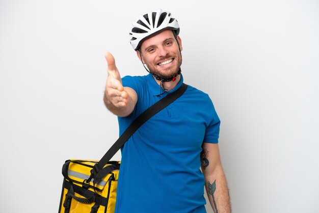 Jeune homme brésilien avec sac à dos thermique isolé sur fond blanc se serrant la main pour conclure une bonne affaire