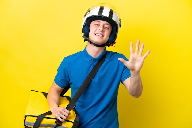 Jeune homme brésilien avec sac à dos thermique isolé sur fond jaune comptant cinq avec les doigts