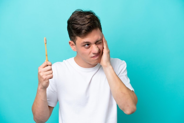 Jeune homme brésilien se brosser les dents isolé sur fond bleu frustré et couvrant les oreilles