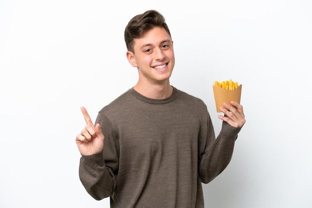 Jeune homme brésilien tenant des frites frites isolées sur fond blanc montrant et levant un doigt en signe du meilleur